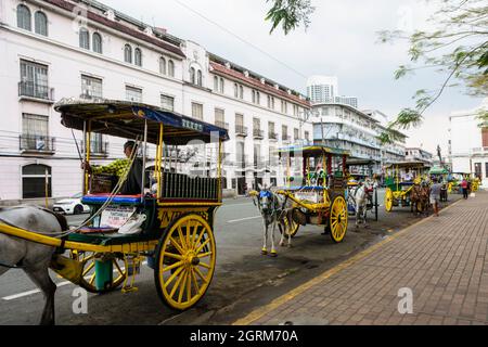 Parked tartanillas (horse drawn carriages with two side-facing benches) in Manila city, Philippines Stock Photo