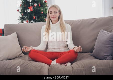 Full length body size photo blonde woman practising yoga sitting alone at home Stock Photo