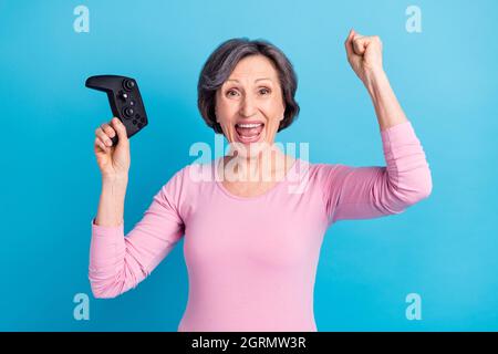 Photo of happy cheerful good mood smiling woman raise fists in victory play playstation isolated on blue color background Stock Photo