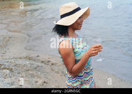 Woman holding a glass of wine with the sea in the background Stock Photo