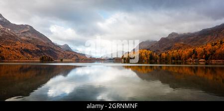Panorama of atumn lake Sils (Silsersee) in Swiss Alps mountains. Colorful forest with orange larch. Switzerland, Maloja region, Upper Engadine. Landscape photography Stock Photo