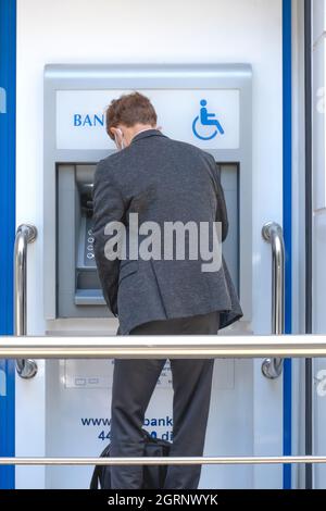 Man using ATM machine to withdraw or deposit money.Standing man depositing money from ATM. Stock Photo