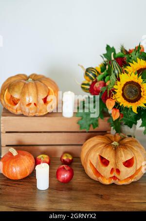 Autumn holiday concept: pumpkins, candles, sunflower and other attributes at the table as Halloween party theme background. Halloween orange pumpkin with evil scary faces. High quality vertical photo Stock Photo