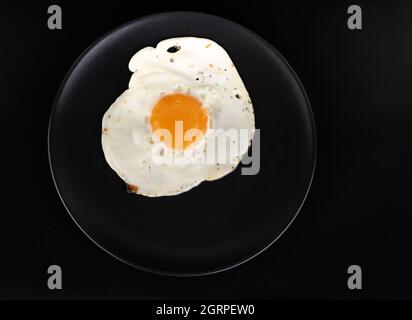 Scrambled eggs with chicken eggs on a black plate on a black background Stock Photo