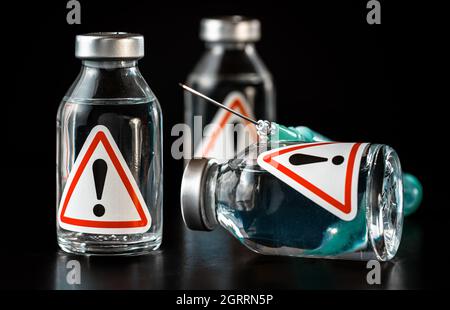 Vaccine bottles with red triangle exclamation mark sign on label, black background Stock Photo
