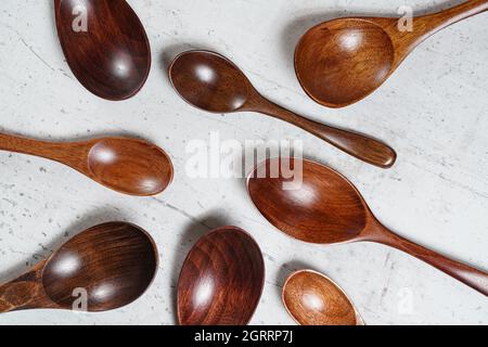 Small spoons made of dark wood, on white working board, view from above Stock Photo