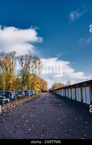 POZNAN, POLAND - Nov 12, 2017: A footpath between a row of locked garage doors and a secured parking lot Stock Photo