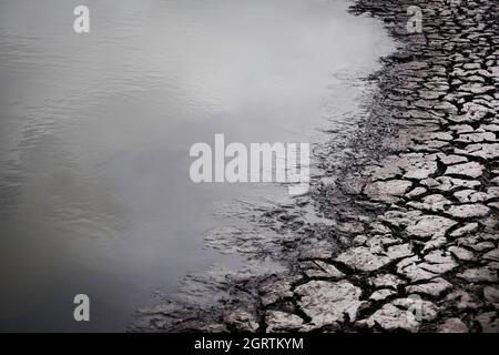 Cracked mud next to lake Stock Photo