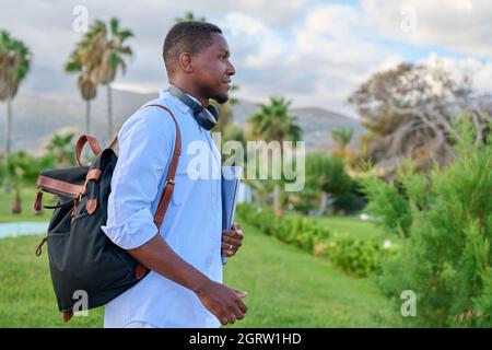 Outdoor portrait of young man with laptop headphones and backpack Stock Photo