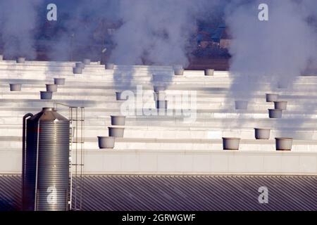 Chimneys with dark smoke on industrial building roof Stock Photo