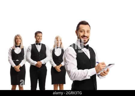 Waiter with a bow tie writing and other waiters standing in the back isolated on white background Stock Photo