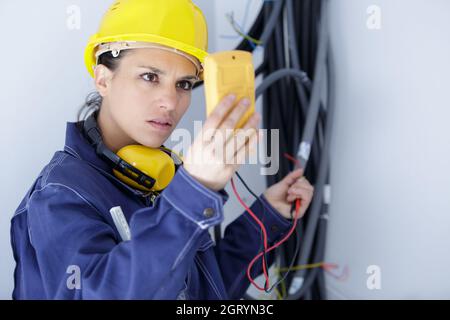 serious female electrician reading multimeter Stock Photo