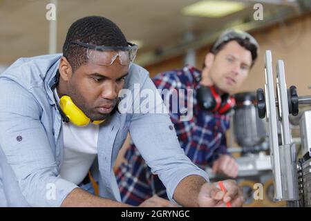 engineer supervising male apprentice in factory Stock Photo