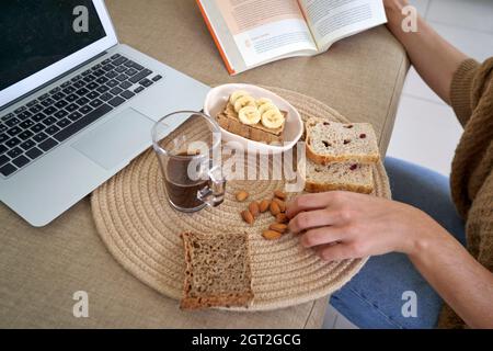 From above shot of tray with served healthful breakfast near laptop on table. Stock Photo