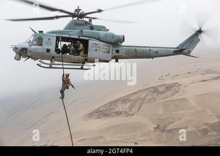 A U.S. Marine with Special Purpose Marine Air-Ground Task Force – UNITAS, descends a rope from a UH-1Y Venom helicopter fast-rope training evolution at Peruvian Marine Corps Base Ancon, Peru, Sept. 26, 2021, during exercise UNITAS LXII. U.S., Brazilian, Chilean, Colombian, Mexican, and Peruvian Marines and members of the Jamaican Defense Force completed a series of training events in order to build trust, enhance confidence and strengthen interoperability to better prepare us for a combined, multinational response to emerging crises or natural disasters. UNITAS is the world's longest-running a Stock Photo