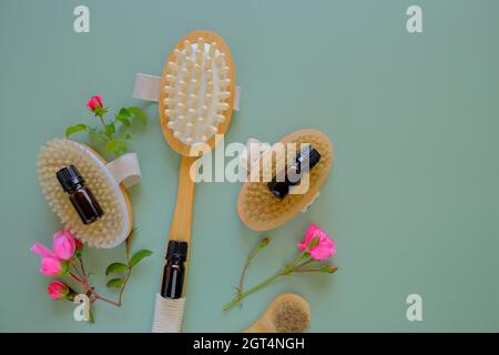 Rose oil. Spa, massage and aromatherapy. Massage brushes set, oil in bottles and rose flowers on a green background.  Stock Photo