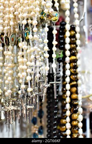 White rosaries with silver crosses and religious jewelries on display in a Catholic store Stock Photo