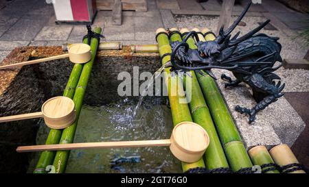 Purification by washing hand at the fountain of sanctuary in Kyoto. Water running from mouth of a dragon at Japan. Entrance of a Japanese shinto templ Stock Photo