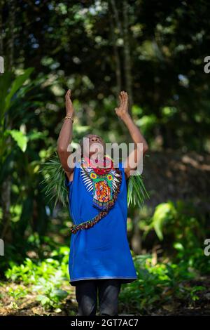 Nueva Loja, Sucumbios / Ecuador - September 2 2020: Elderly indigenous shaman of Cofan nationality performing a healing ritual with his arms raised in Stock Photo