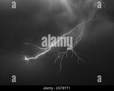 Bright lightning bolt with many side branches strikes down to earth in a  river landscape Stock Photo - Alamy