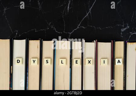Plastic tiles with letters spelling DYSLEXIA on book. Dyslexia is a reading disorder. Learning concept Stock Photo