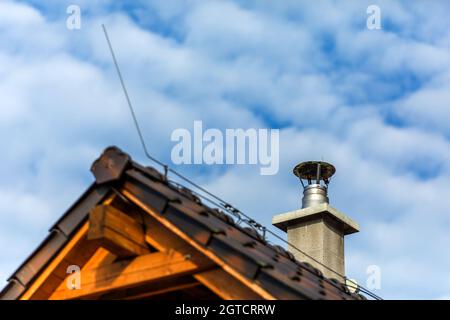 Stainless steel metal chimney pipe on the roof of the house against the blue sky. Stainless steel chimney on house. Stock Photo