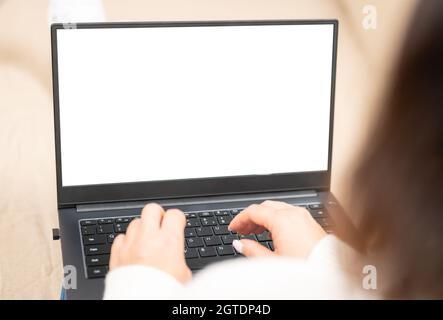 Woman on sofa working on laptop with mockup blank screen. Empty copyspace on monitor for advertisement, online shopping website, social media site. sh Stock Photo