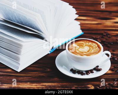Close-up Of Coffee In Cup With Open Book On Table