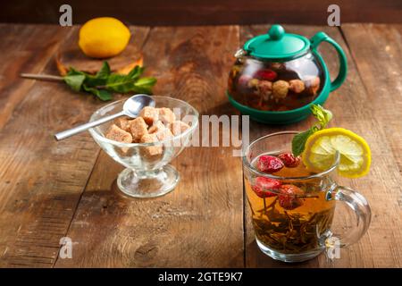 Green Tea In A Glass Cup With Strawberries Mint And Lemon On A Wooden Table And A Teapot