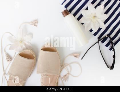 Summer Flat lay. Summer sandals, white flowers, sunglasses and a white bottle.Top view. Creative background. Stock Photo