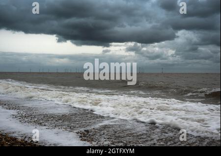 Looking out to Scroby Sands wind farm Great Yarmouth with heavy dark rain clouds and the tide coming in Stock Photo