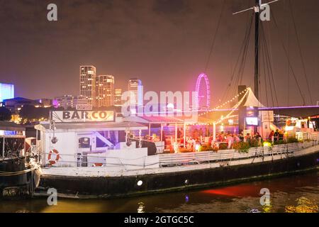 Floating bar on the Thames with southbank at night in the background Stock Photo