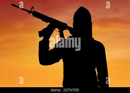 Silhouette Man Holding Gun Against Sky During Sunset