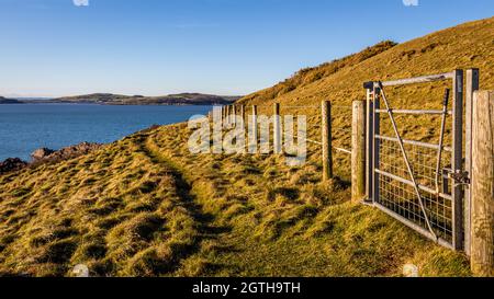 A gate and a rugged coastal trail along the solway firth on a sunny winters day in Dumfries and Galloway, Scotland Stock Photo