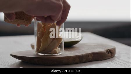 man pack freeze dried mango in glass jar on olive wood board, wide photo Stock Photo
