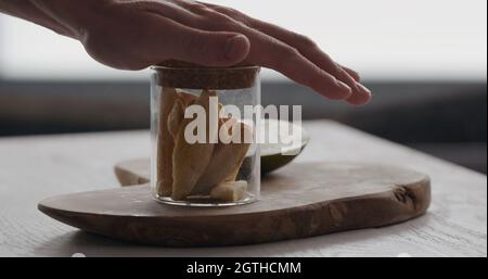 man pack freeze dried mango in glass jar on olive wood board, wide photo Stock Photo