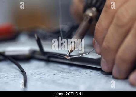 Wires being soldered together with a soldering iron. Melting solder wire on soldering iron tip Stock Photo