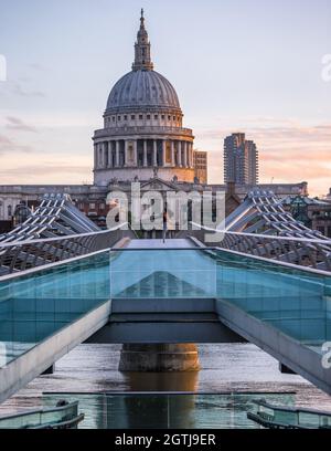 A male dancer on Millennium Bridge with the imposing St. Paul's cathedral in the background at sunrise in London. Stock Photo