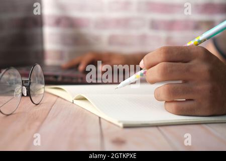 man hand writing on notepad and using laptop  Stock Photo
