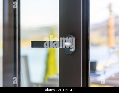 Aluminum glazed window detail. Metal or plastic door frame open closeup view. Energy efficient, safety profile, blur outdoor background Stock Photo