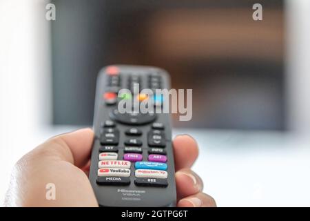 Greece Stoupa. September 27 2021. TV remote control in male hand, Watching television and channel switching concept. Stock Photo