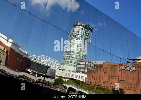 Reflections buildings off mirrored facade of Birmingham New Street station with distorted image of Rotunda and Bullring shopping Stock Photo