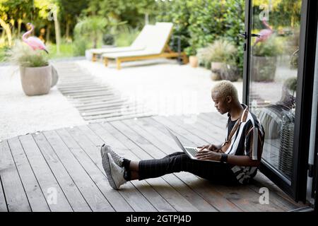 Black man using laptop computer on terrace at home Stock Photo