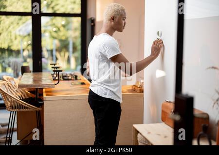 Black man choosing temperature on thermostat Stock Photo