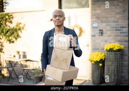 Black man standing with parcels near his house Stock Photo