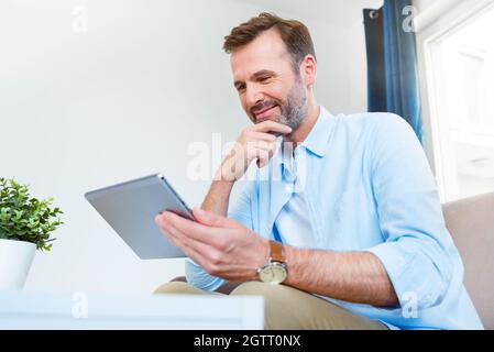 Handsome businessman working from home. Using app on tablet to telecommuting or sales reporting Stock Photo