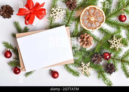 Invitation template for Christmas and new year. A holiday card with an envelope and a branch of a fir tree, oranges and Christmas toys on a white back Stock Photo