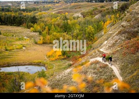 Two mountain bikers ride the Bowmont trail system in autumn colours above Dale Hodges Park in Calgary Alberta Canada Stock Photo