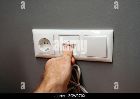 Male hand inserting in wall socket outlet RJ45 internet cable ethernet Stock Photo