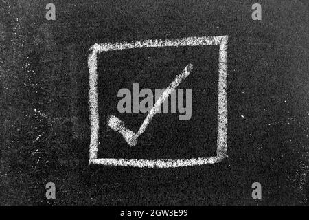 White color chalk hand drawing in right checkmark in square box shape on black board background Stock Photo